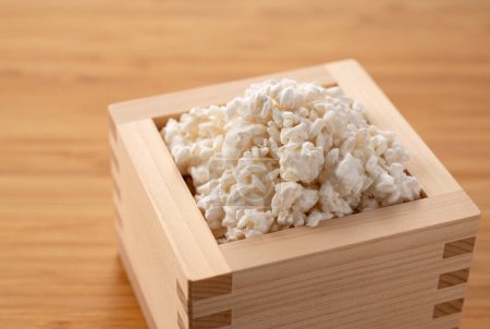 Photo for Rice koji in a Masu box placed against a wooden background. Koji mold. Koji is fermented rice. - Royalty Free Image