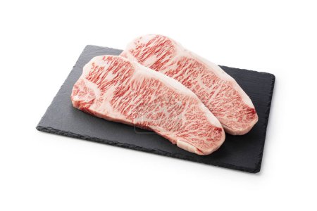 Fresh raw beef steak placed on a stone plate against a white background. Wagyu beef steak.