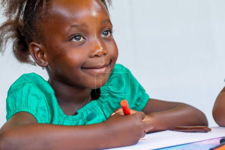Téléchargez les photos : Close-up portrait of cute African girl painting with wax crayon. Isolated against a white background. - en image libre de droit