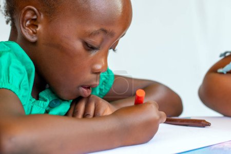 Photo for Close-up side view portrait of African girl painting with wax crayon. Isolated against a white background. - Royalty Free Image