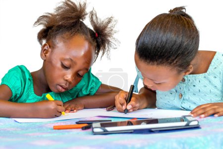 Foto de Two little African kids drawing with wax crayons at table. Isolated against a white background. - Imagen libre de derechos