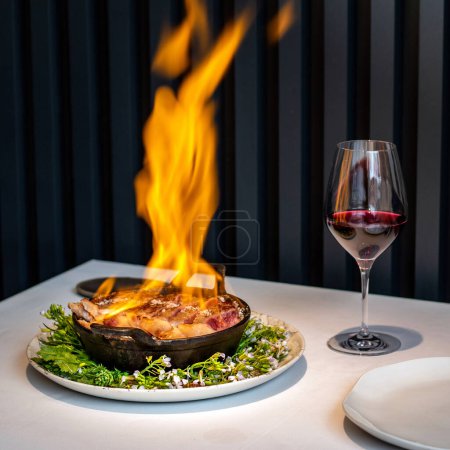 Photo for Close up of chef preparing beef sirloin steak flambe at table in gourmet restaurant. - Royalty Free Image