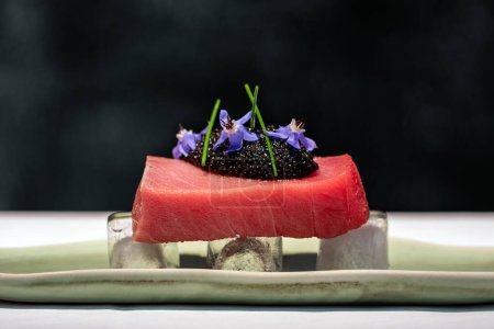 Téléchargez les photos : Extrême gros plan de la portion de thon rouge sur la glace avec du caviar de béluga sur fond sombre. - en image libre de droit