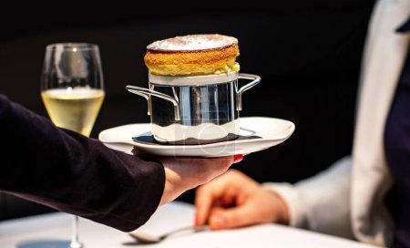 Foto de Primer plano de camarera sirviendo aperitivo souffl de esponja a mujer en restaurante con copa Champaign en fondo. - Imagen libre de derechos