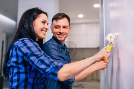 Foto de Joven feliz pareja pintando su nuevo hogar interiores con rodillos de pintura - Imagen libre de derechos