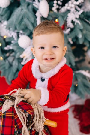 Photo for Portrait of little boy on rocking horse on the background of the Christmas tree. - Royalty Free Image