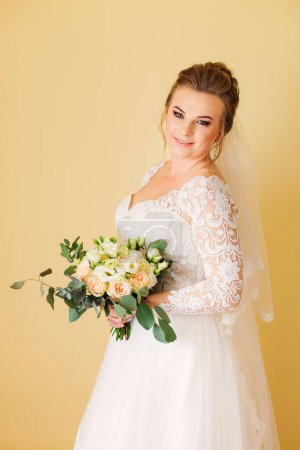 Foto de Novia en un vestido de lujo sostiene un ramo de bodas y mira a la cámara. - Imagen libre de derechos