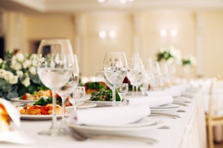 Foto de Primer plano de las gafas de vino vacías en la mesa de servir con platos. recepción de boda. - Imagen libre de derechos