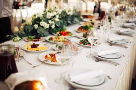 Téléchargez les photos : Table posée à une réception de mariage décorée de fleurs. délicieux aliments et boissons. - en image libre de droit