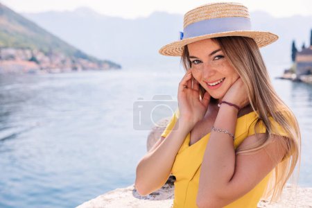 Photo for Close up shot of good looking female tourist enjoys free time outdoor near sea on beach, looks at camera during leisure on sunny summer day. - Royalty Free Image