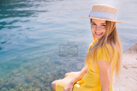 Téléchargez les photos : Belle jeune femme avec chapeau de paille près de la mer par jour ensoleillé en été - en image libre de droit