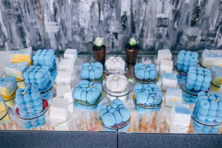 Foto de Deliciosa barra de caramelo en una recepción de boda de lujo. una mesa exclusiva y cara con postres modernos en blanco y azul - Imagen libre de derechos