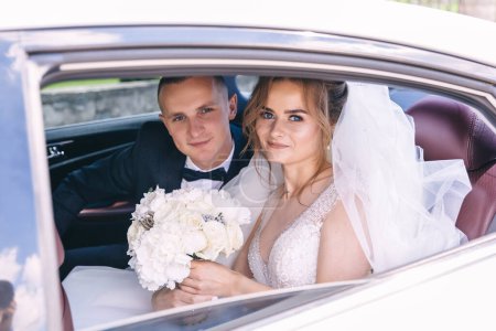 Foto de Hermosa novia recién casada y novio posan dentro del coche después de la ceremonia. - Imagen libre de derechos