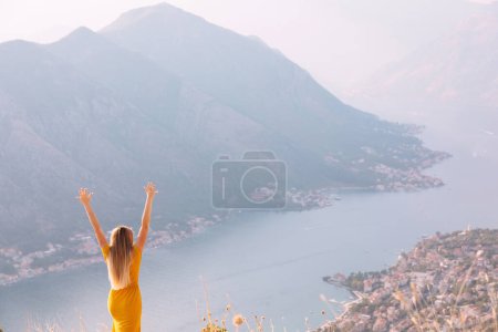 Foto de La chica de la vista trasera levanta las manos. Admira la ciudad de Kotor en Montenegro y muestra lo feliz que está
. - Imagen libre de derechos