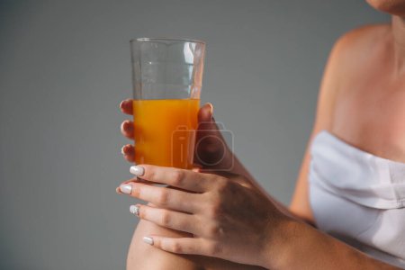 Téléchargez les photos : Image rapprochée d'une femme tenant à la main un verre de jus d'orange - en image libre de droit