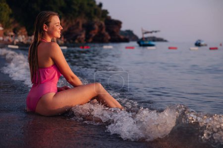 Téléchargez les photos : Heureuse femme souriante jouant dans l'eau et nageant dans les vagues sur la plage de la mer océan. - en image libre de droit