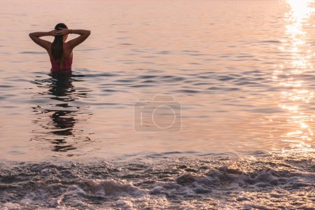 Téléchargez les photos : Femme se détendre dans l'eau au coucher du soleil. - en image libre de droit
