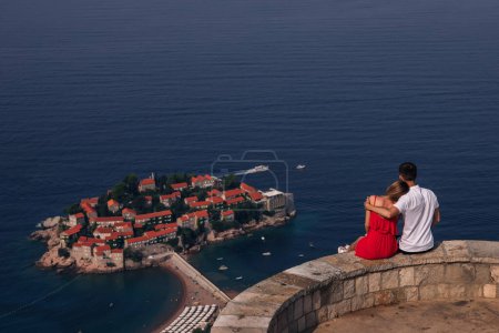 Foto de Romántica pareja joven enamorada sobre la orilla del mar sobre la isla de Sveti Stefan en Budva, Montenegro. Viajar. Vacaciones. Familia
. - Imagen libre de derechos