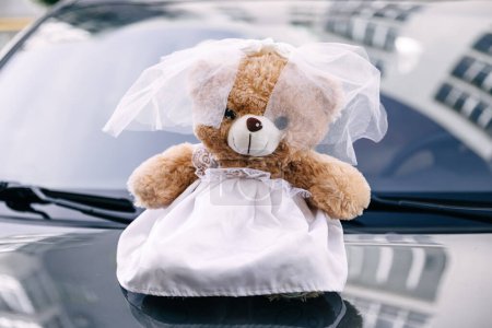Photo for Teddy bear female in wedding dress on decorated car hood - Royalty Free Image