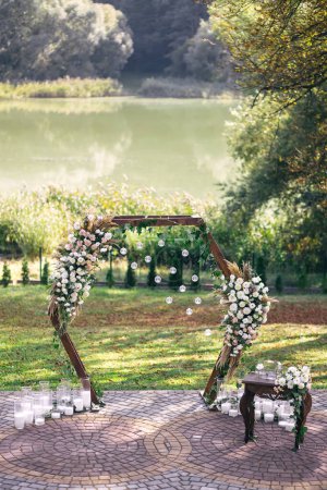 Foto de Wedding arch decorated with white flowers and greenery outdoors, copy space. Wedding setting. Floral composition - Imagen libre de derechos