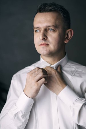 Photo for Handsome man groom buttoning his shirt in a hotel room. - Royalty Free Image