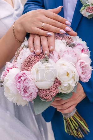 Photo for Hands with wedding rings and flower bouquet - Royalty Free Image