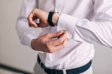 Photo for The man wears silver cufflinks on the cuff of a white shirt. The groom's hands fasten the cufflinks to the sleeve. Groom's morning - Royalty Free Image