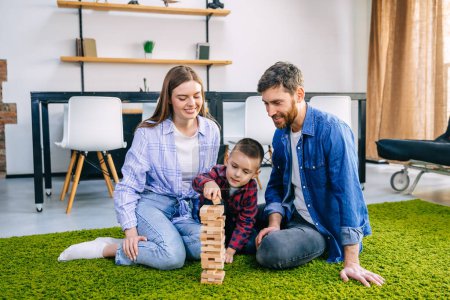 Photo for Loving young caucasian family with a boy sitting on the living room floor playing with bricks. - Royalty Free Image