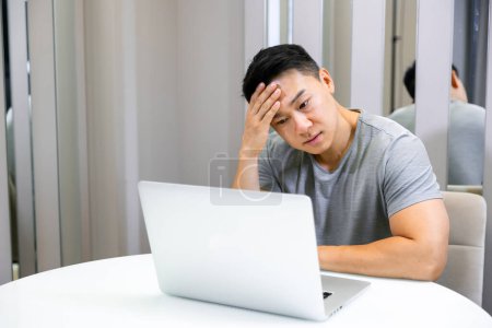 Téléchargez les photos : Un jeune homme fatigué qui travaille à la maison a mal à la tête après une longue journée de travail - en image libre de droit