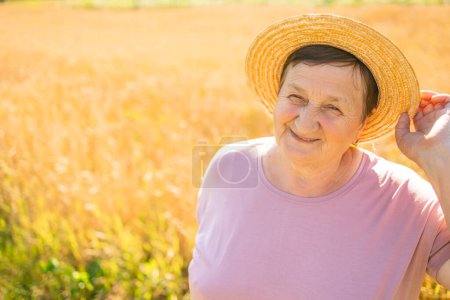 Foto de Retrato de una mujer mayor sonriendo con sombrero de paja mirando a la cámara al aire libre. Granjera mayor en el jardín. Copiar espacio - Imagen libre de derechos
