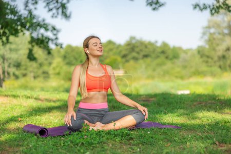 Photo for Woman practicing yoga in lotus position at park - Royalty Free Image