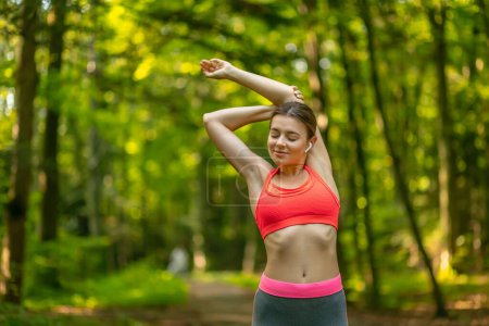 Foto de Chica deportiva haciendo ejercicio antes de correr en el parque, estirando sus músculos al aire libre, sintiéndose saludable y motivada, espacio para copiar - Imagen libre de derechos