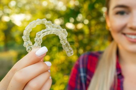 Photo for Female hand holding Invisalign, the invisible braces aligner at face woman background. Correction of teeth concept - Royalty Free Image