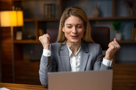 Foto de Excited office worker receiving good news in email on laptop, motivated happy  female employee getting promoted or rewarded celebrating great result achievement win opportunity - Imagen libre de derechos