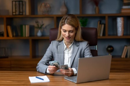 Téléchargez les photos : Successful business woman counting money at office desk in slow motion. Smiling girl rejoicing with good deal in workplace. - en image libre de droit