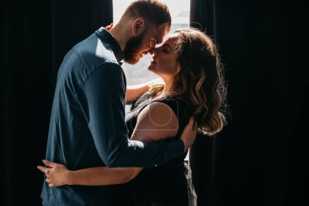 Couple in love - woman and husband hug and kissing on window background