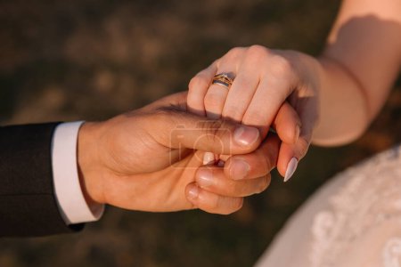 Téléchargez les photos : Jeune couple marié tenant la main, cérémonie de mariage le jour du coucher du soleil - en image libre de droit