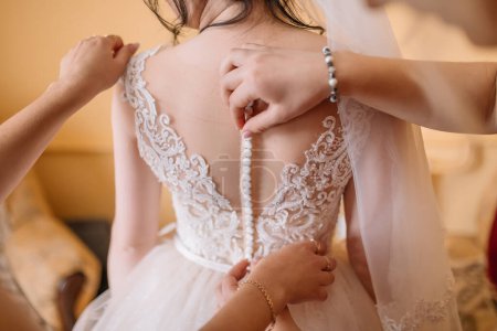 Téléchargez les photos : Demoiselle d'honneur aide la mariée à s'habiller - en image libre de droit