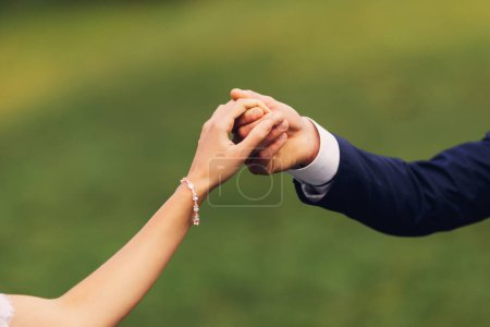 Téléchargez les photos : Mains d'un homme et d'une femme tenant ensemble. La fille a un beau bracelet en or avec des diamants sur son poignet. Bijoux - en image libre de droit