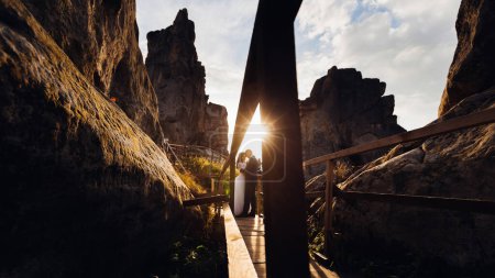 Téléchargez les photos : Une belle silhouette d'un homme et d'une femme le jour de leur mariage près de hauts rochers sur le fond du coucher de soleil - en image libre de droit