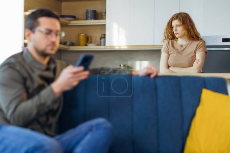 Photo for Conflict, young couple, family, man and woman. An angry woman take takes offense at a man who constantly uses and plays on the phone, does not pay attention - Royalty Free Image
