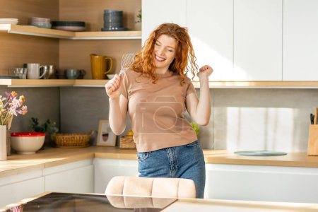 Téléchargez les photos : Joyeux jeune femme dansant dans la cuisine. Elle est heureuse et relaxante pendant le week-end. - en image libre de droit