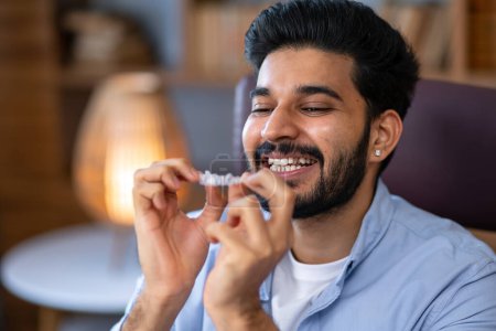 Téléchargez les photos : Homme heureux mettant des aligneurs dentaires invisibles clairs dans sa bouche pour redresser ses courbes dents - en image libre de droit