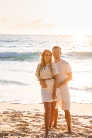 Foto de Una pareja casada en una playa tropical al atardecer. Feliz joven pareja de luna de miel durante las vacaciones junto al mar - Imagen libre de derechos