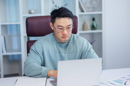 Téléchargez les photos : Homme d'affaires utilisant un ordinateur portable au bureau. Asiatique homme, entrepreneur, propriétaire de petite entreprise travaillant en ligne. - en image libre de droit