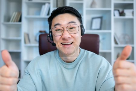 Photo for Cheerful happy adult asian guy showing like thumb up hands at camera, smiling, laughing, speaking on video conference call. Satisfied customer, user head shot portrait. - Royalty Free Image