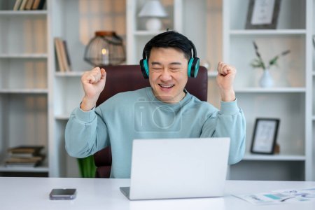Téléchargez les photos : Heureux détendu asiatique homme porter sans fil casque fini travail écouter de la musique préférée, avoir du plaisir pendant la pause - en image libre de droit