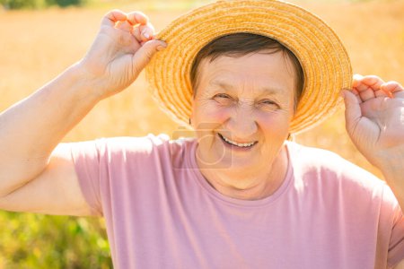 Foto de Retrato de una jardinera jubilada con sombrero de paja mirando a la cámara al aire libre. Granjera mayor en el jardín, primer plano - Imagen libre de derechos