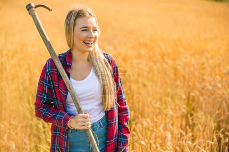 Photo for Portrait of a cheerful woman, gardener holding garden tools in her hands in a wheat field. Copy space - Royalty Free Image