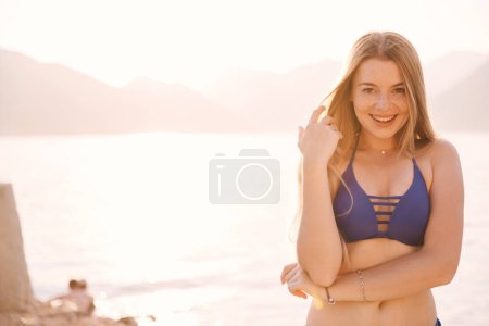 Photo for Portrait of attractive woman standing at beach and looking at camera. Happy smiling girl relaxing at seaside during summer vacation. Copy space - Royalty Free Image